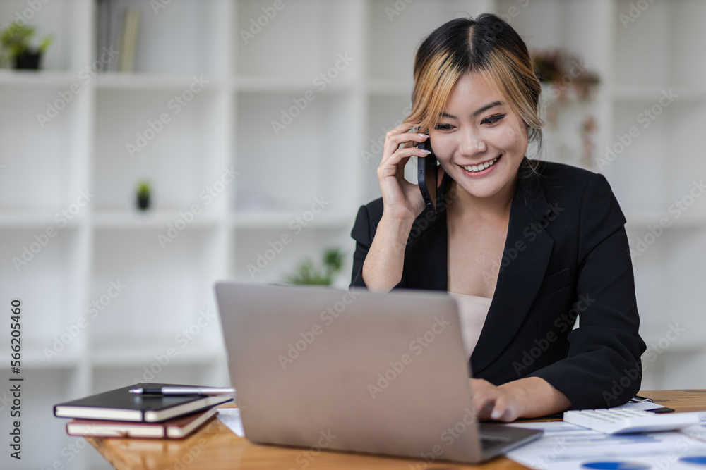 Businesswoman in office working with laptop and documents on desk while talking on phone with customer. Businesswoman in office working with laptop and documents on desk while talking on phone with customer.