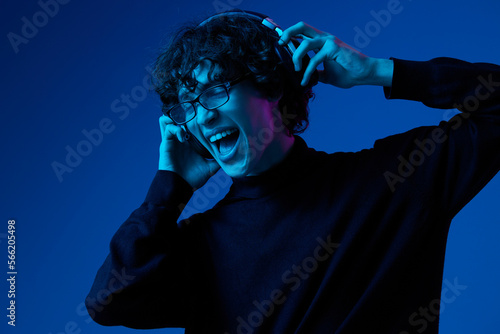 Fotografiet Teenage man wearing headphones listening to music and dancing and singing open m
