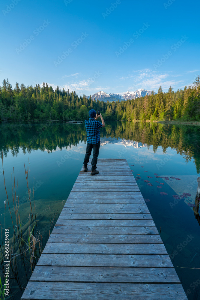 Man photographing Crestasee lake with smarthpone, Switzerland Man photographing Crestasee lake with smarthpone, Switzerland