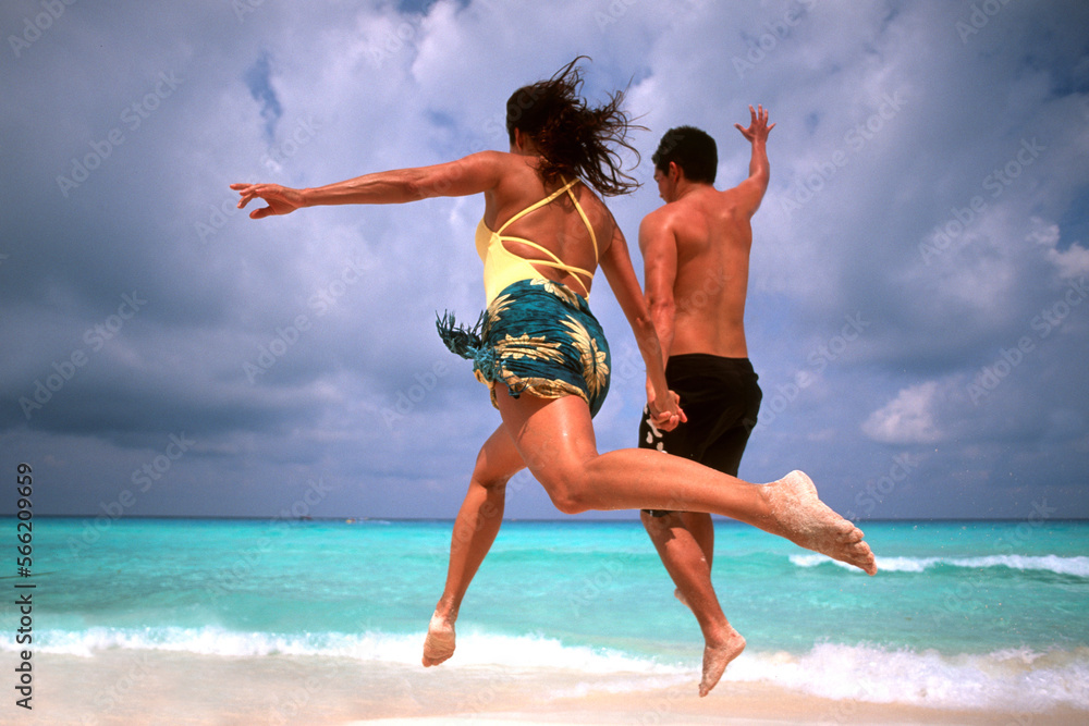Abstract of fun couple running and jumping in Cancun on beach Mexico Abstract of fun couple running and jumping in Cancun on beach Mexico