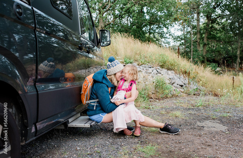 mother and daughter hugging and laughing whist camping in a camper van photo