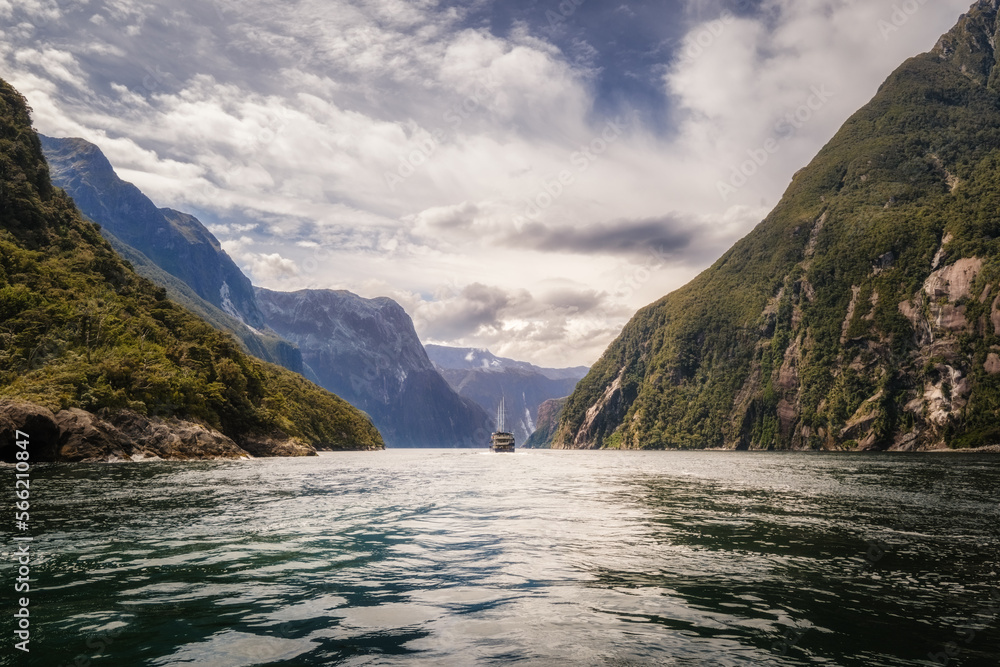 Tour boat passing through the dramatic landscape of Milford Sound in Fiordland on the South Island of New Zealand