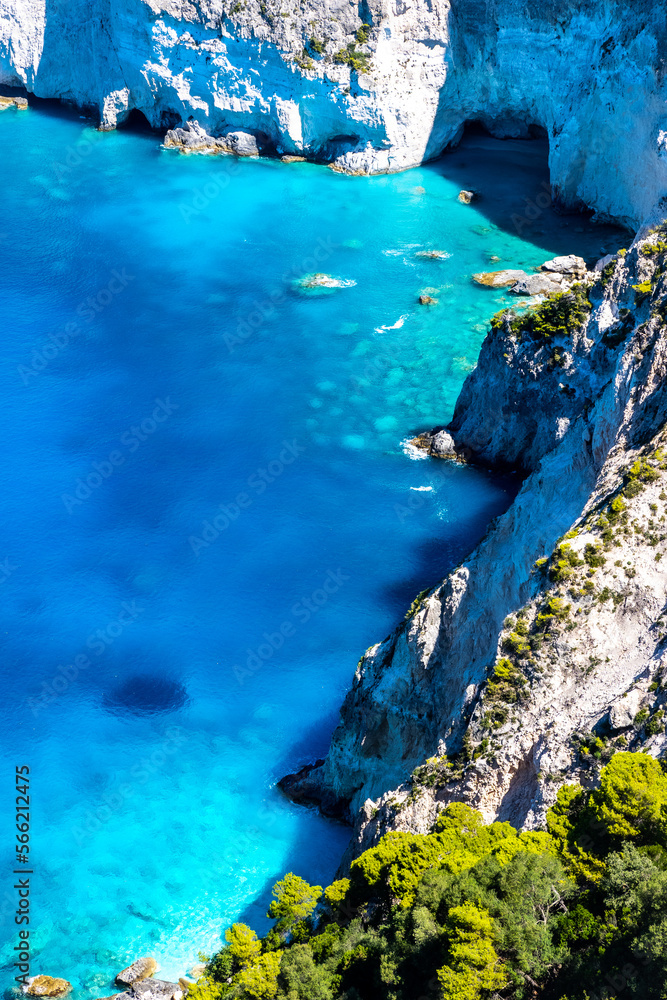 Fototapeta premium Beautiful crystal clear blue and turquoise waters next to a rugged, overgrown coastline that makes a wonderful play of colors, Keri, Zakynthos, Greece