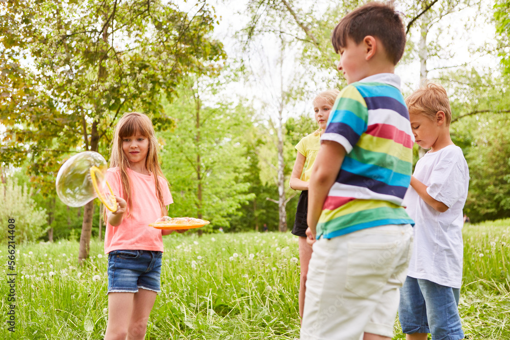 Fototapeta premium Girl making bubble by friends in green garden