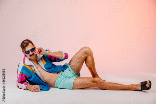 Back in time 90s 80s lifestyle concept. Studio footage of stylish cheerful young man in vintage retro jacket on light pink background, candy-colored fashions, creativity, emotions, facial expression
