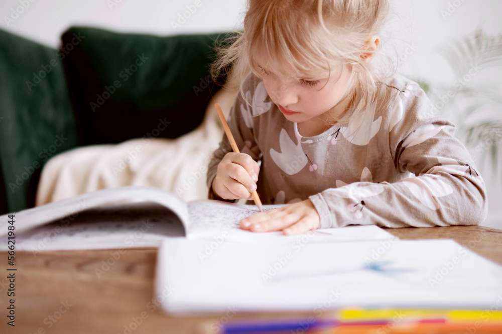 A cute preschool girl is creative and learning to draw with colored pencils A cute preschool girl is creative and learning to draw with colored pencils