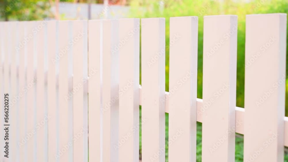 Smooth camera movement along a white wooden fence close-up on a blurred background in sunny summer weather. Homemade neat stylish street fence Smooth camera movement along a white wooden fence close-up on a blurred background in sunny summer weather. Homemade neat stylish street fence