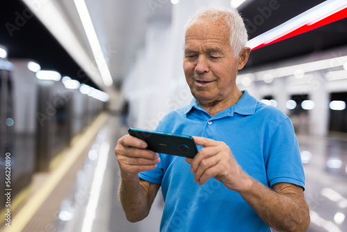 Senior man with smartphone waiting in subway station