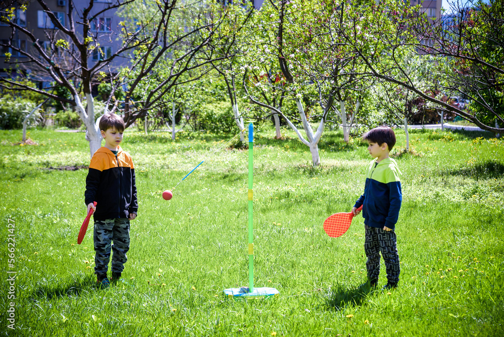 Fototapeta premium Two friends are playing tetherball swing ball game in summer camping. Two boy brother happy leisure healthy active time outdoors concept