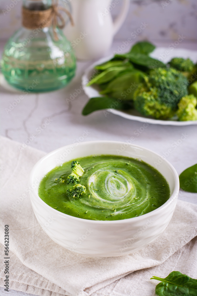 Fresh broccoli puree soup in a bowl on the table. Vegetarian food. Vertical view Fresh broccoli puree soup in a bowl on the table. Vegetarian food. Vertical view