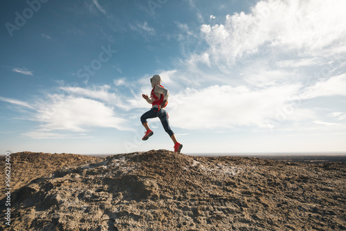 Woman trail runner cross country running on desert hill top