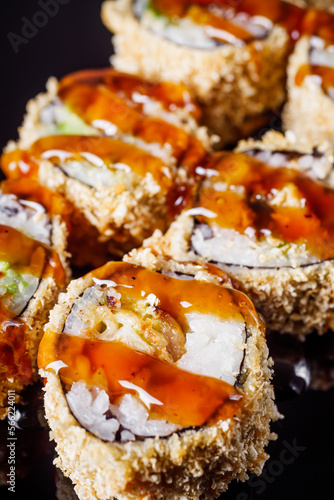 hot sushi roll tempura with eel shrimp crab salmon cream cheese cucumber avocado unagi on a black mirror background