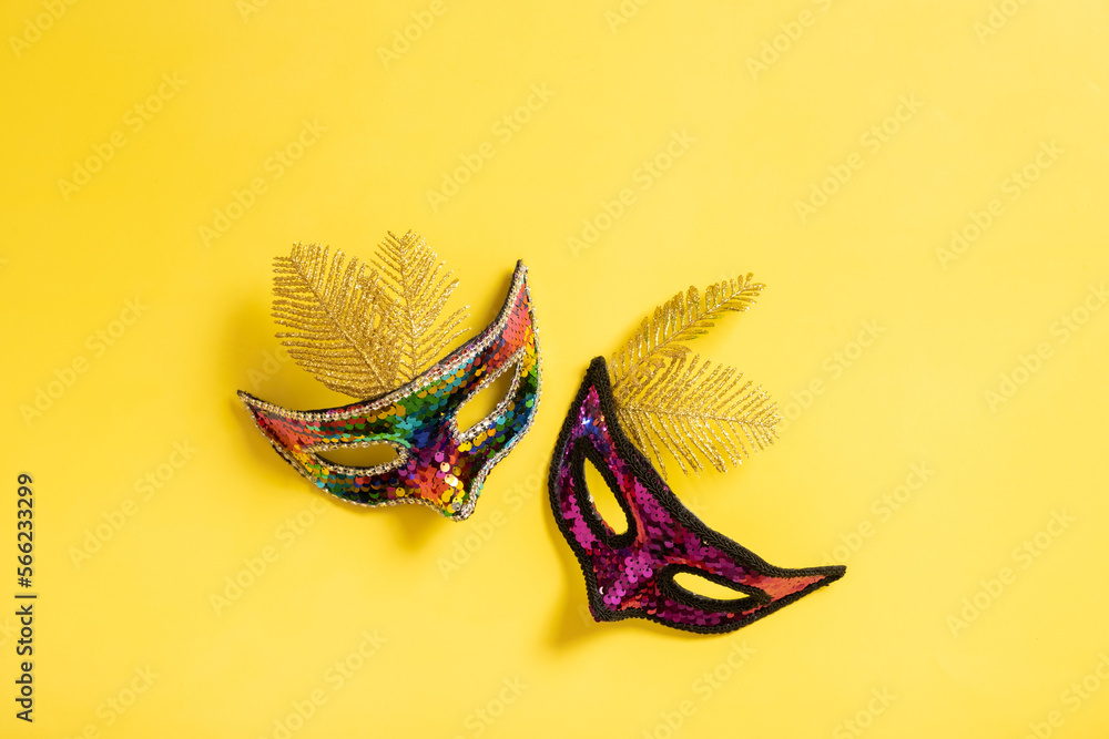 Festive face masks for carnival celebration on colored banner background flat lay, top view