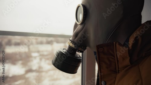 waiting for a nuclear catastrophe. a man in a gas mask looks out the window