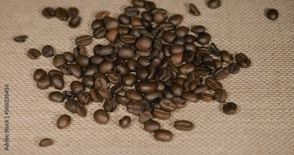 Roasted coffee beans falling on a jute covered table Roasted coffee beans falling on a jute covered table