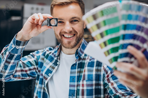 Man working in printing house with paper and paints photo