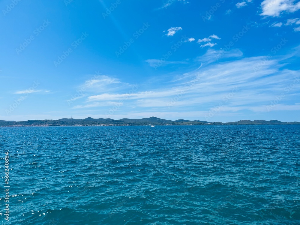 Blue seascape, blue sea and blue sky, mountains silhouette background