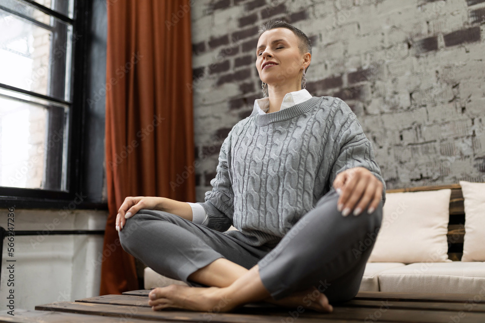 mature woman sitting at home on table in yoga pose relaxing mature woman sitting at home on table in yoga pose relaxing