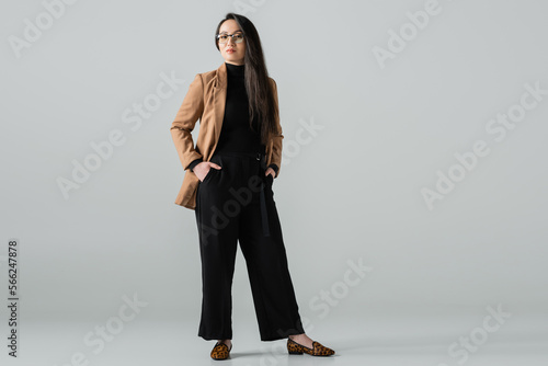 Картината върху платно full length of confident asian woman in beige blazer and black pants standing wi