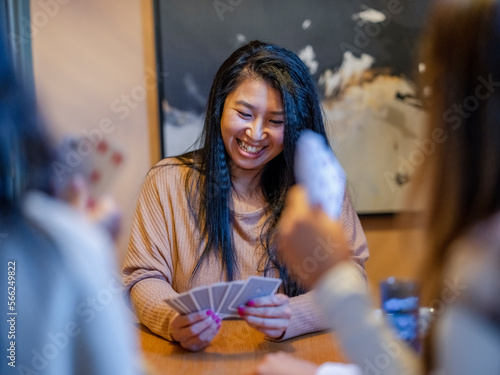 Smiling friends playing cards at home © Cultura Creative