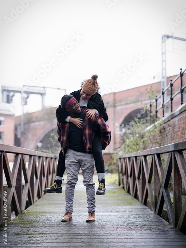 Smiling man carrying girlfriend on back on footbridge