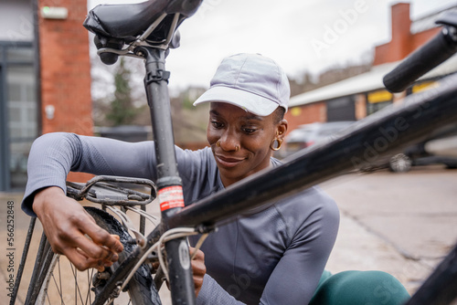 Smiling woman adjusting bicycle wheel