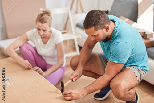 Husband and wife assembling new furniture - home renovation concept.