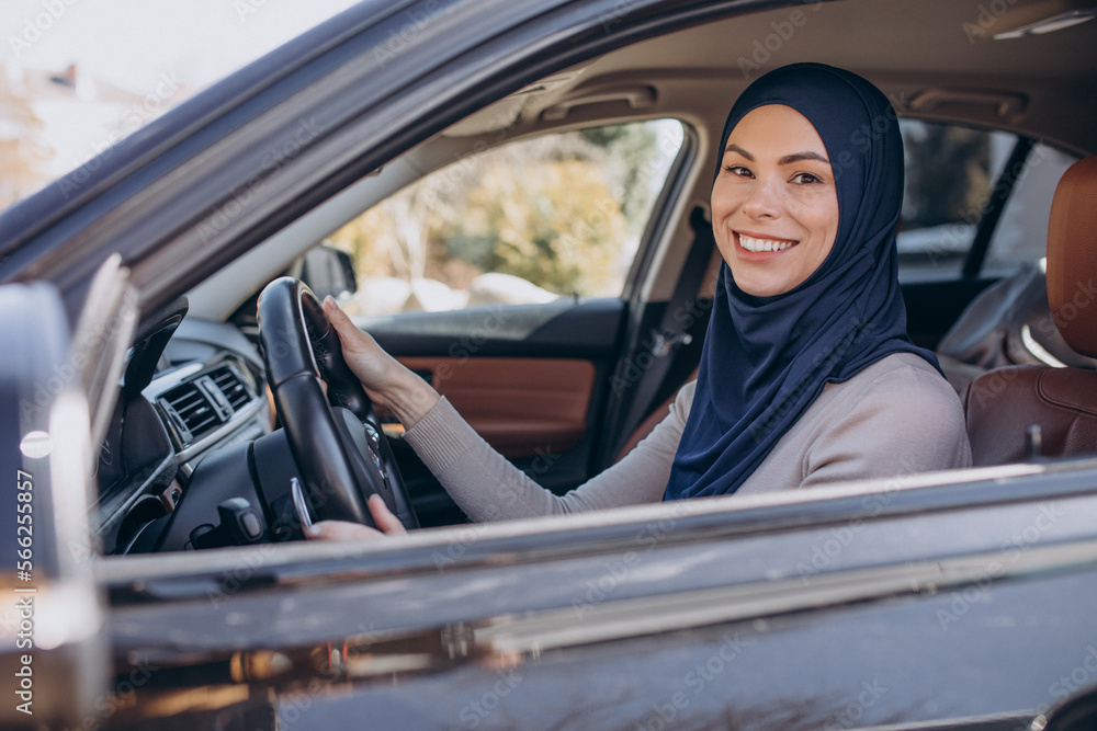 Young muslim woman sitting in her car and looking into the mirror