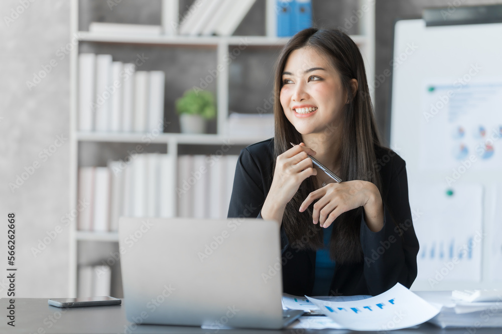 Beautiful Asian female bookkeeper doing online accounting with laptop in private accounting office, balance sheet and stock market statistics. Beautiful Asian female bookkeeper doing online accounting with laptop in private accounting office, balance sheet and stock market statistics.