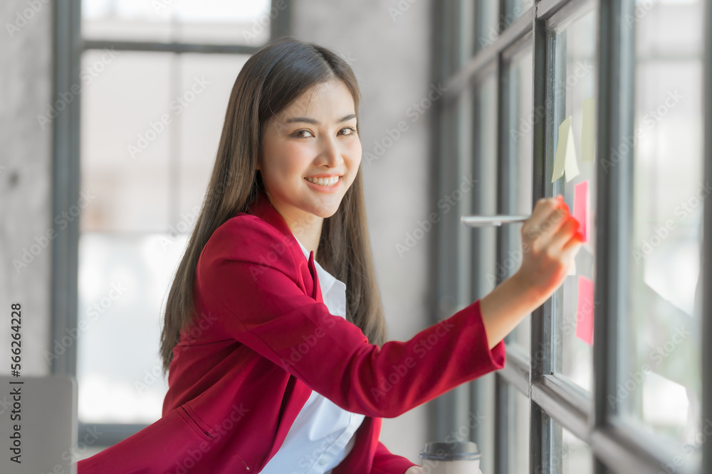 Pretty asia business woman bookkeeper brainstorming and working in modern office workplace with sticky notes or post it at windows.