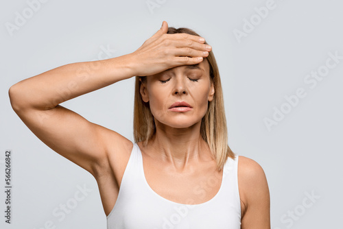 Middle aged woman suffering from terrible strong head pain photo