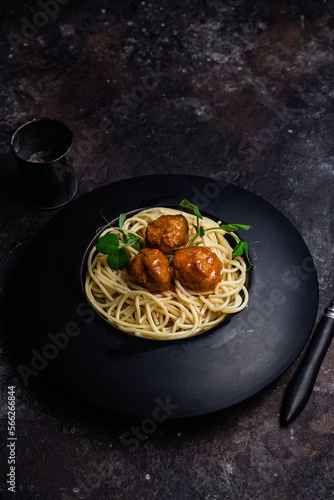 Spaghetti with meatballs in a black plate