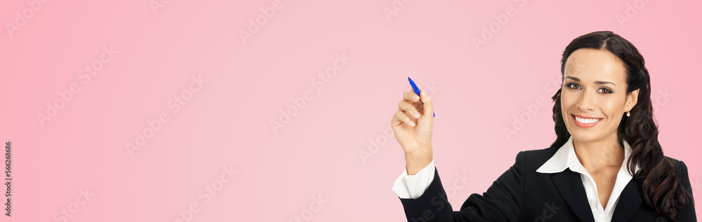 Happy smiling cheerful beautiful young business woman writing or drawing something on screen or transparent glass, by blue marker, isolated over rose pink background Happy smiling cheerful beautiful young business woman writing or drawing something on screen or transparent glass, by blue marker, isolated over rose pink background
