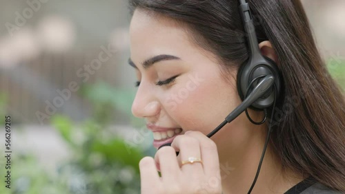 young businesswoman wearing a headset and talking with her customer line. customer service representative and call center work-at-home concept: close-up angle and handheld shot.