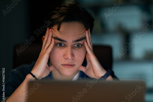 Closeup of stressed young man looking at laptop screen