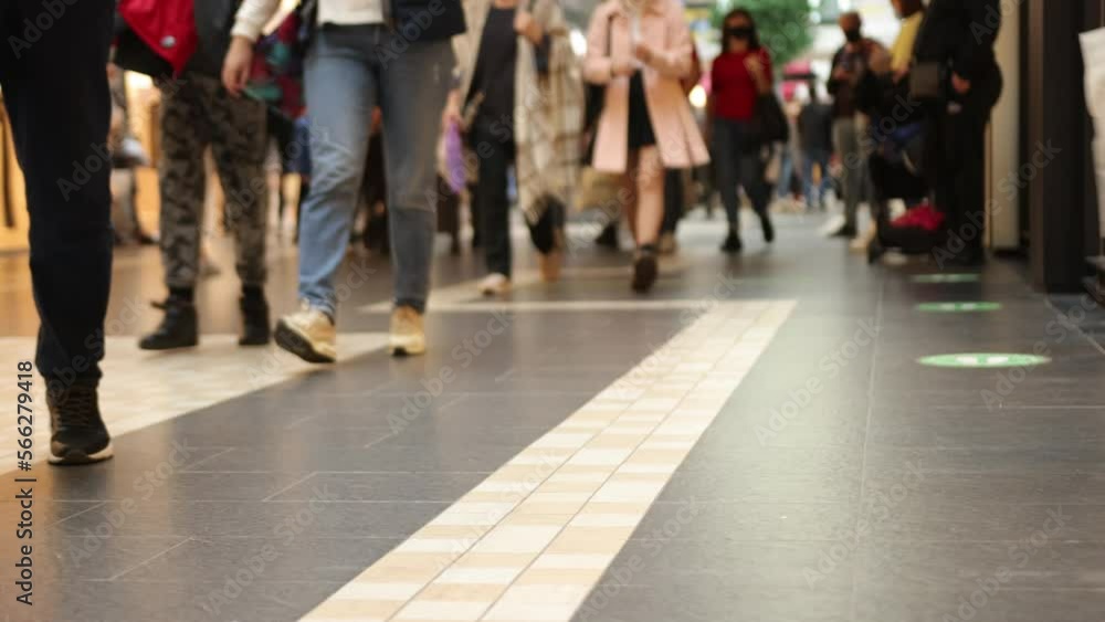 legs closeup, people walking, crowd walking. In midst of shopping, legs close-up in shopping mall, selective focus is placed upon modern floor featuring crowd walking legs closeup, people walking, crowd walking. In midst of shopping, legs close-up in shopping mall, selective focus is placed upon modern floor featuring crowd walking