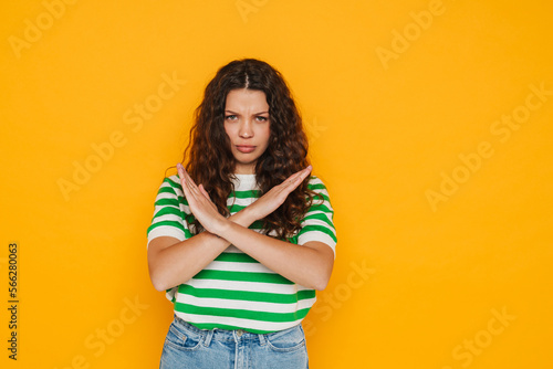Young girl frowning while standing with crossed hands showing stop gesture isolated