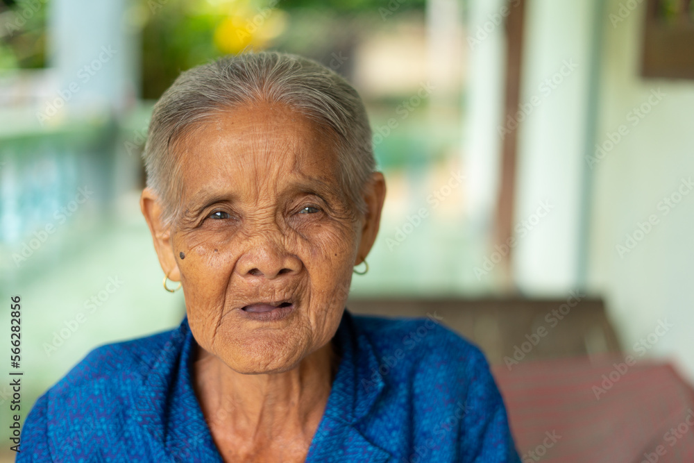 Smiling Grandma or an old woman with short hair Asian in a blue shirt. He was raising his face, happily. by looking at the camera at home Smiling Grandma or an old woman with short hair Asian in a blue shirt. He was raising his face, happily. by looking at the camera at home