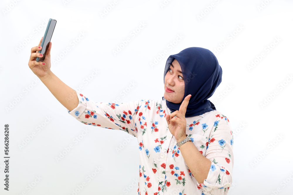 Asian muslim woman standing while photographing her self. Isolated on white background Asian muslim woman standing while photographing her self. Isolated on white background