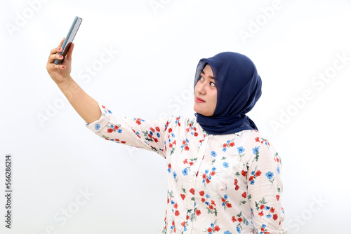 Asian muslim woman standing while photographing her self. Isolated on white background