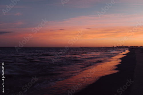 Fototapeta Naklejka Na Ścianę i Meble -  Long exposure amazing color sunset at the ocean beach with red sky and orange horizon. Copy space. Concept of travel destination ocean and nature beauty. Waves and sea.