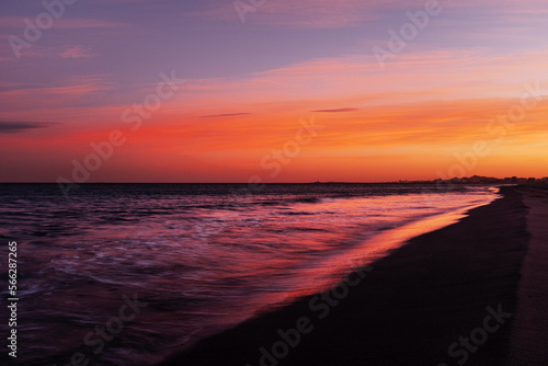 Long exposure amazing color sunset at the ocean beach with red sky and orange horizon. Copy space. Concept of travel destination ocean and nature beauty. Waves and sea.