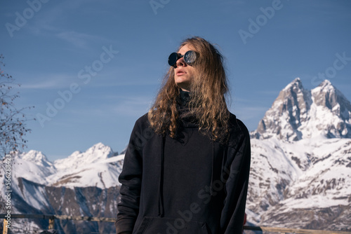 Young stylish man portrait in high mountain peaks. Vacation in mountain resort, sunny day, sports and fashion © Annatamila