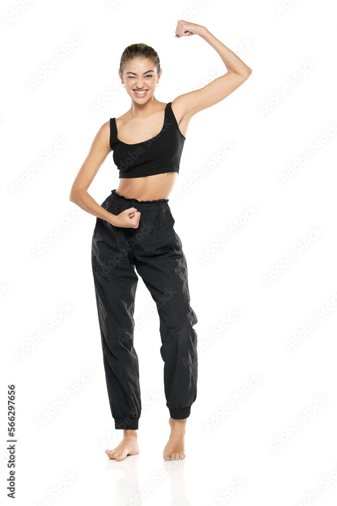 a young barefeet happy woman in black sweatpants and a tank top on a white background a young barefeet happy woman in black sweatpants and a tank top on a white background