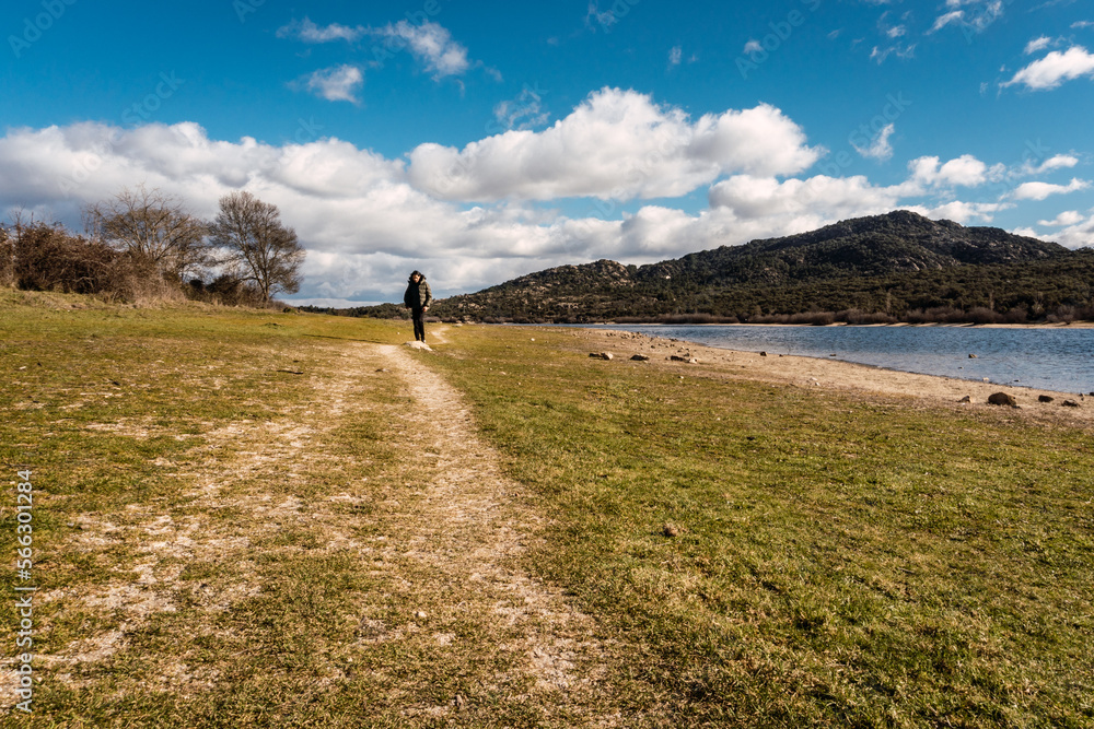 Fototapeta premium A man walking on a dirt road next to a lake