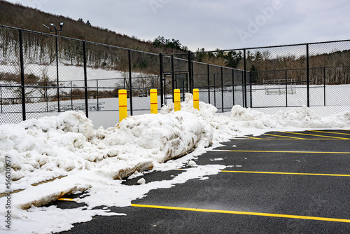4 Large Yellow Concrete Pillars are placed on the edge of the parking lot to protect the Tennis Court fences from being damaged during snow plowing in the winter in Upstate NY.
