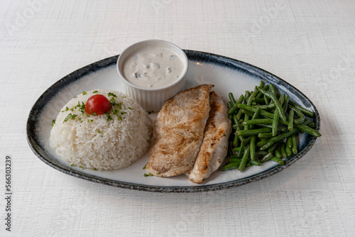 Paris, France - 01 18 2023: Middle East dishe culinary Still Life. Fried cutlet with tomatoes, green bean and rice accompaniement and White sauce photo