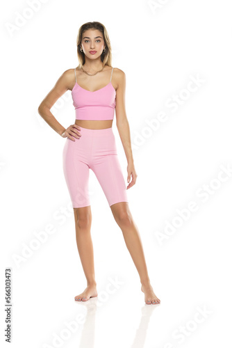 a young barefeet woman in pink short leggings and top posing on a white background