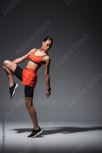 full length of sportive and young african american woman in sneakers exercising on grey. © LIGHTFIELD STUDIOS