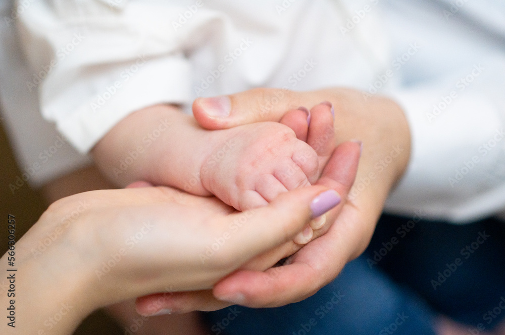 Parents hold in their hands the small hand of their newborn baby at